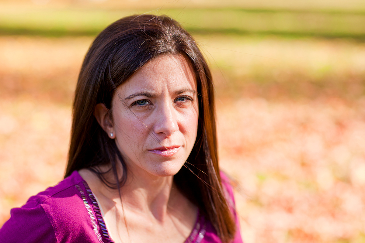 White woman, looking serious, in rural setting